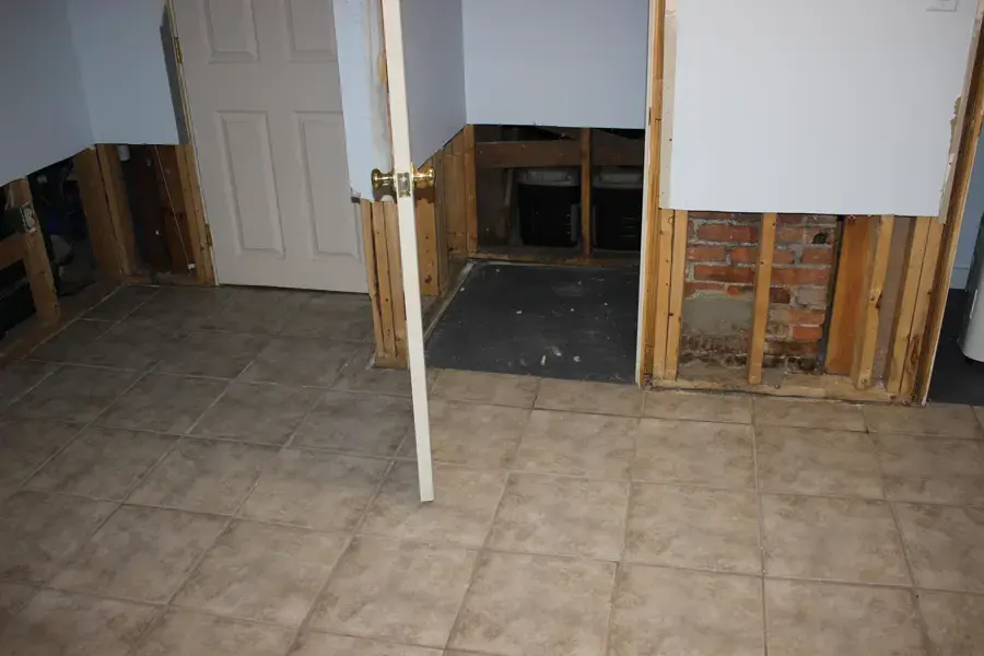 Flood cut drywall removed in a tiled room to expose wet wall material after a water loss