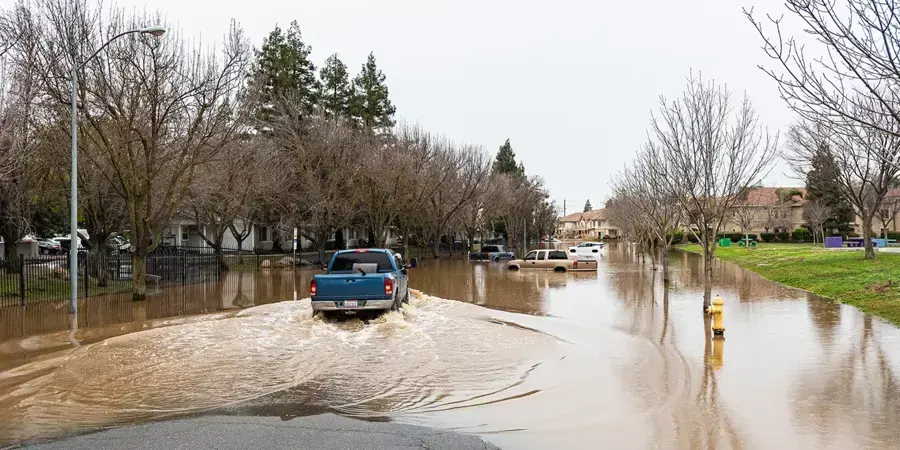 Pickup truck driving through a flooded residential street after a winter storm